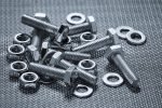 Many bolts, nuts and washers on a steel background.